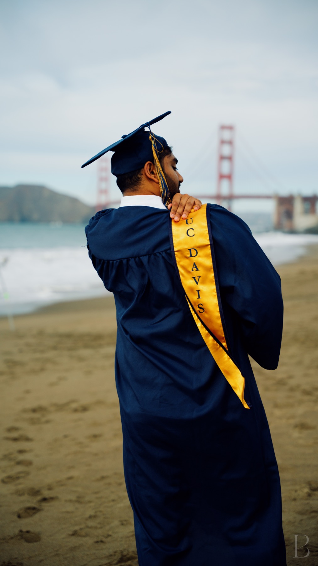 Graduate in cap and gown looking out toward the Golden Gate